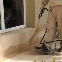 General pest control technician spraying exterior perimeter around a home in Green Bay, WI